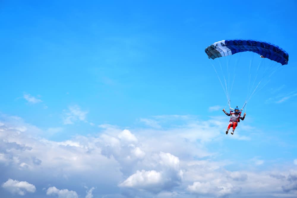 Skydiver in the air. Blue parachute and blue sky.