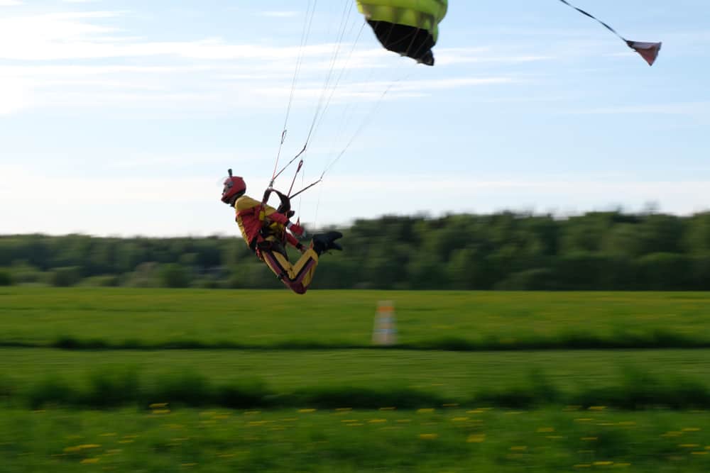 A skydiver / swooper flying over a green field at high speed.